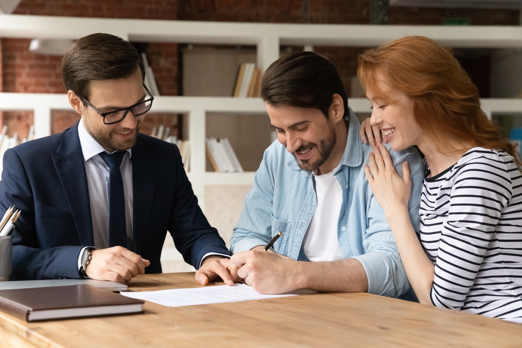 Excited young Caucasian couple sign contract make deal buy house